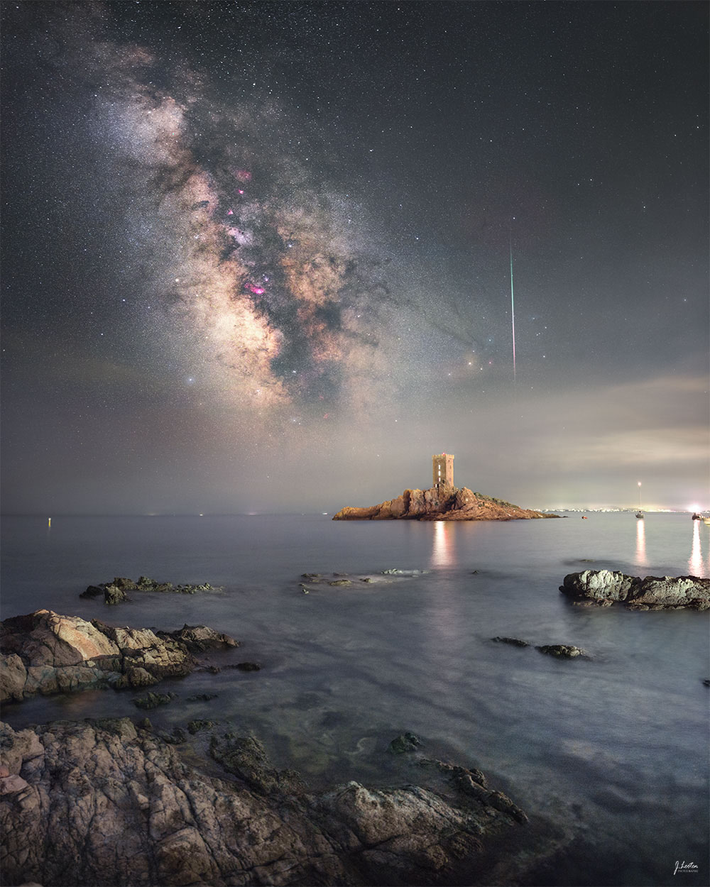 Malerischer felsiger Strand am Mittelmeer im französischen Le Dramont mit der Insel île d’Or island im Vordergrund, dahinter leuchten die Milchstraße und ein Meteor der Perseiden.