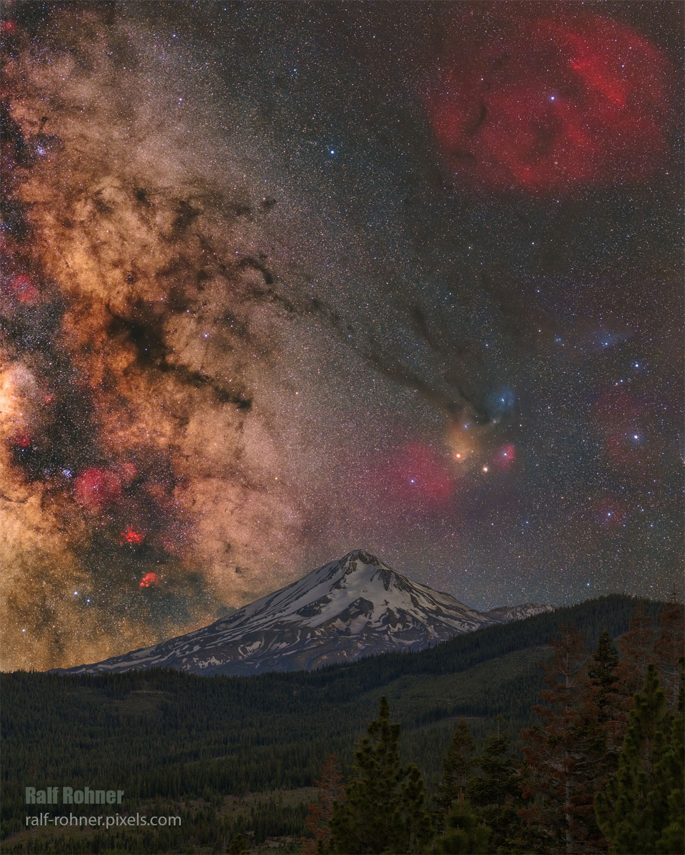 Das Bild zeigt den schneebedeckten Berg Mount Shasta in Kalifornien und im Hintergrund links die Milchstraße und rechts das farbige Sternenfeld des Sternbilds Ophiochus.