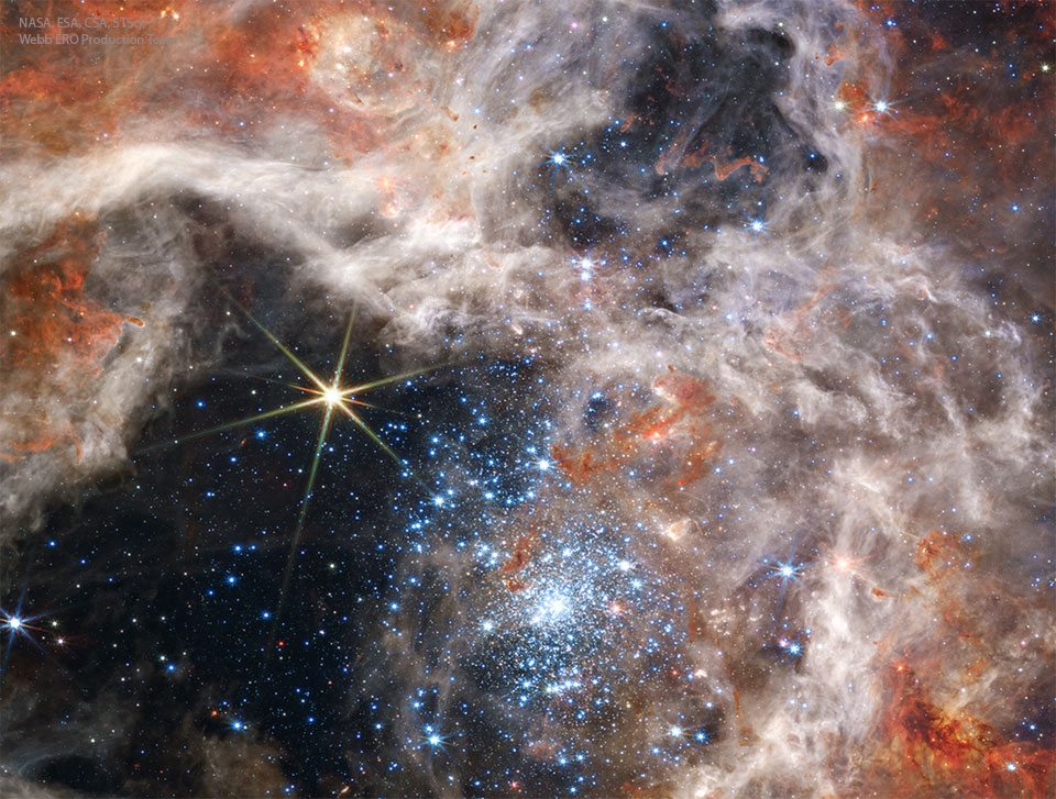 Das Bild zeigt den Sternhaufen R136 im Infrarotlicht, aufgenommen mit dem Weltraumteleskop Webb. Das vordere Bild ist im nahen Infrarotlicht, während das darüber gelegte Bild im mittleren Infrarotlicht aufgenommen wurde.