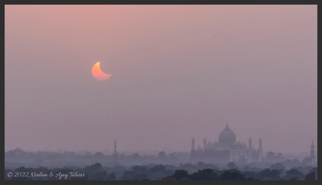 Das Bild zeigt die partielle Sonnenfinsternis vom 25. Oktober 2022 am dunstigen Himmel über dem Tadsch Mahal in der indischen Stadt Agra.