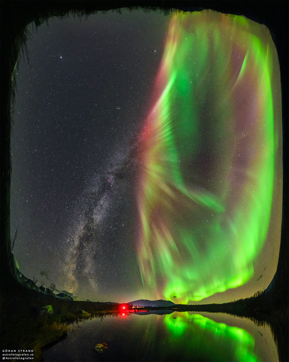 Das Bild zeigt ein Polarlicht als Blume, deren Stiel die Milchstraße ist, über einem See in Abisko in Schweden.