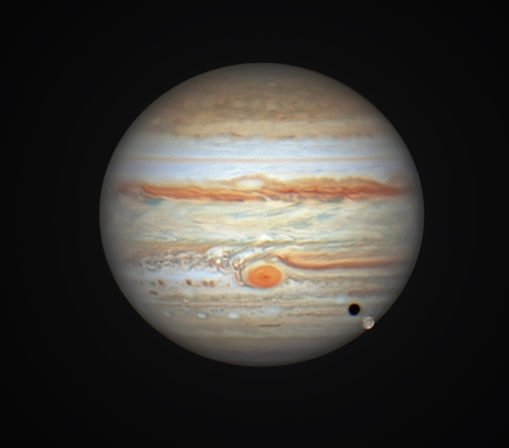 Das Bild zeigt Jupiter mit dem großen Roten Fleck und einen Transit des Mondes Io mit Schatten
