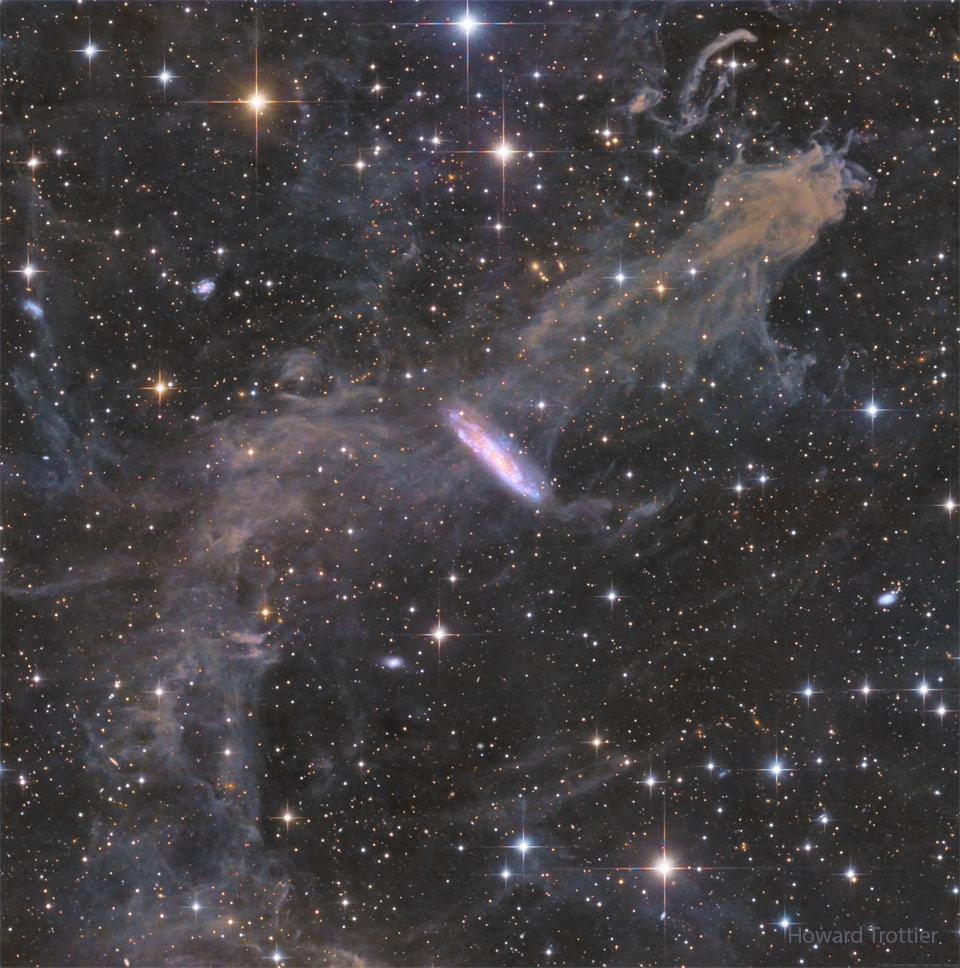 Das Bild wurde in der Sierra Nevada fotografiert, es zeigt die Galaxie NGC 7497, die zufällig hinter dem Nebel MBM 54 im Sternbild Pegasus liegt.