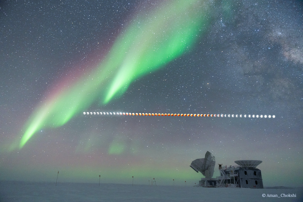 Das Bild zeigt den Mond, wie er während der totalen Mondfinsternis am 8. November über der Amundsen-Scott-Südpolstation parallel zum Horizont über den Himmel zog. Darüber leuchtet ein Polarlicht.