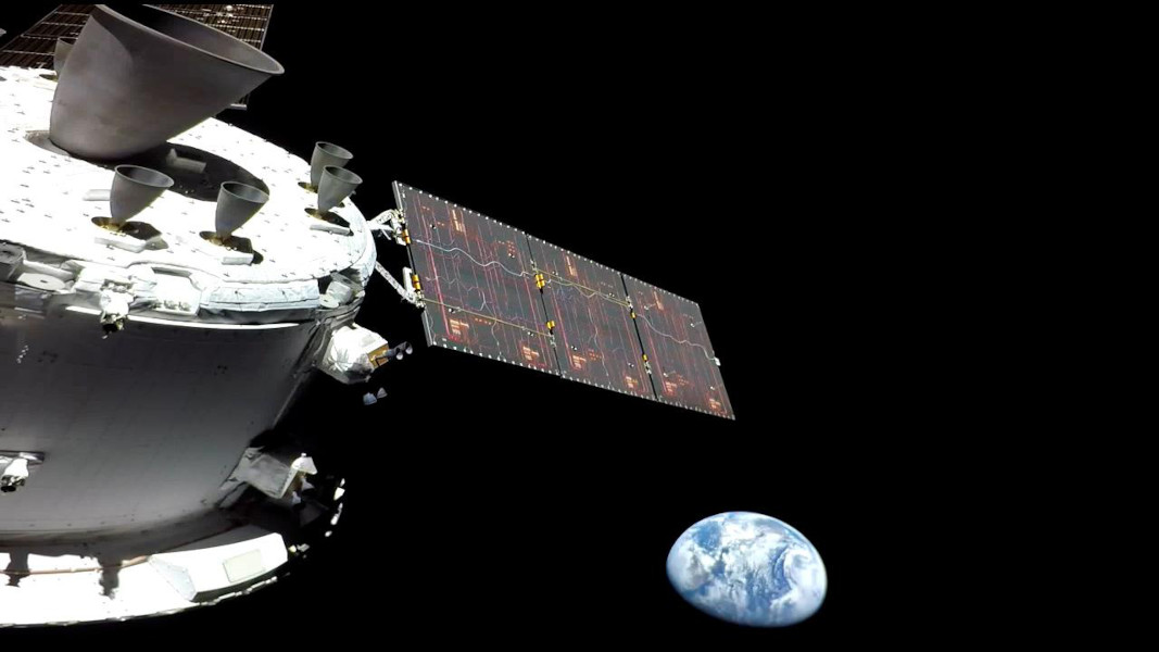 Das Bild zeigt die Triebwerke des Manöversystems des Raumschiffs Orion und ein Solarpaneel, im Hintergrund leuchtet die Erde.