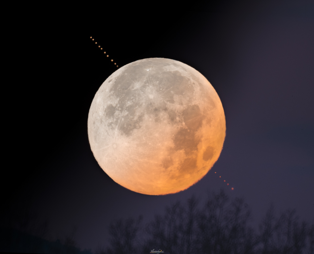 Das Bild zeigt, wie der Vollmond am Horizont vor dem Planeten Mars vorbeizieht.