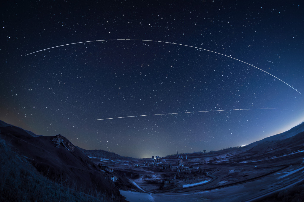 Sternklarer Himmel mit den Spuren der Raumstationen Tiangong und ISS über einer verlassenen Mine in Achada do Gamo in Portugal.