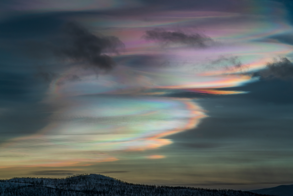 Über Kilpisjärvi in Finnland leuchten perlmuttfarbene Wolken, die wie vom Wind verweht wirken.