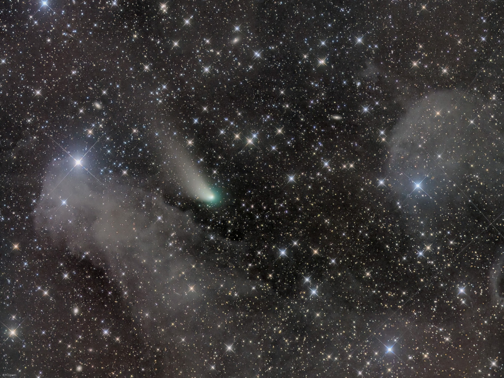 Das mit Sternen gefüllte Bild zeigt auch zwei graue Wolken und den Kometen ZTF. Sein Schweif zeigt nach links oben, er hat einen weißen Kopf mit grünlichem Rand.