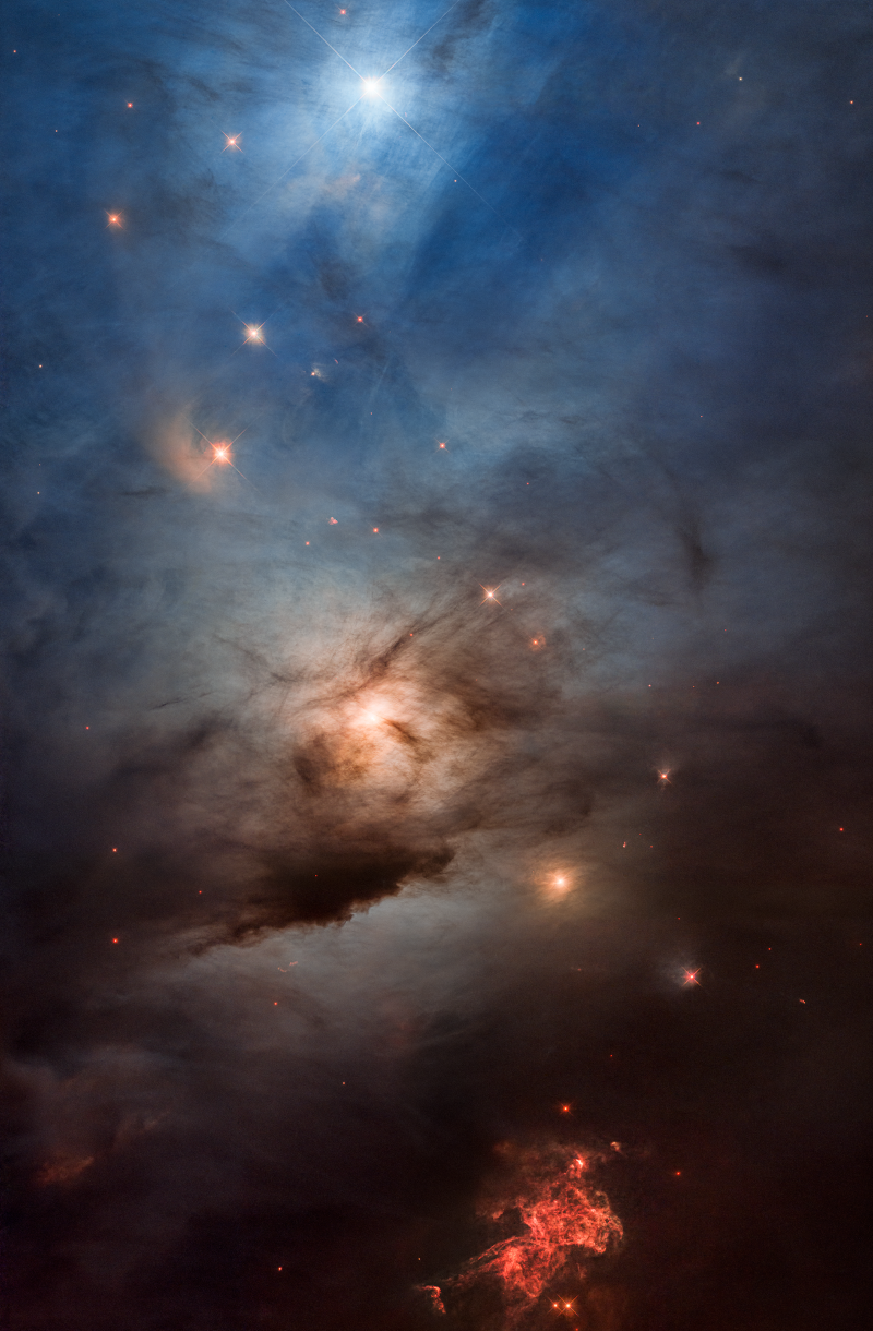 Der obere Bildteil ist von blauen Nebeln bedeckt, oben leuchtet hinter den Nebeln ein Stern. In der Mitte ist ein Stern in Nebeln verborgen, unten leuchtet ein roter, faseriger Nebel.