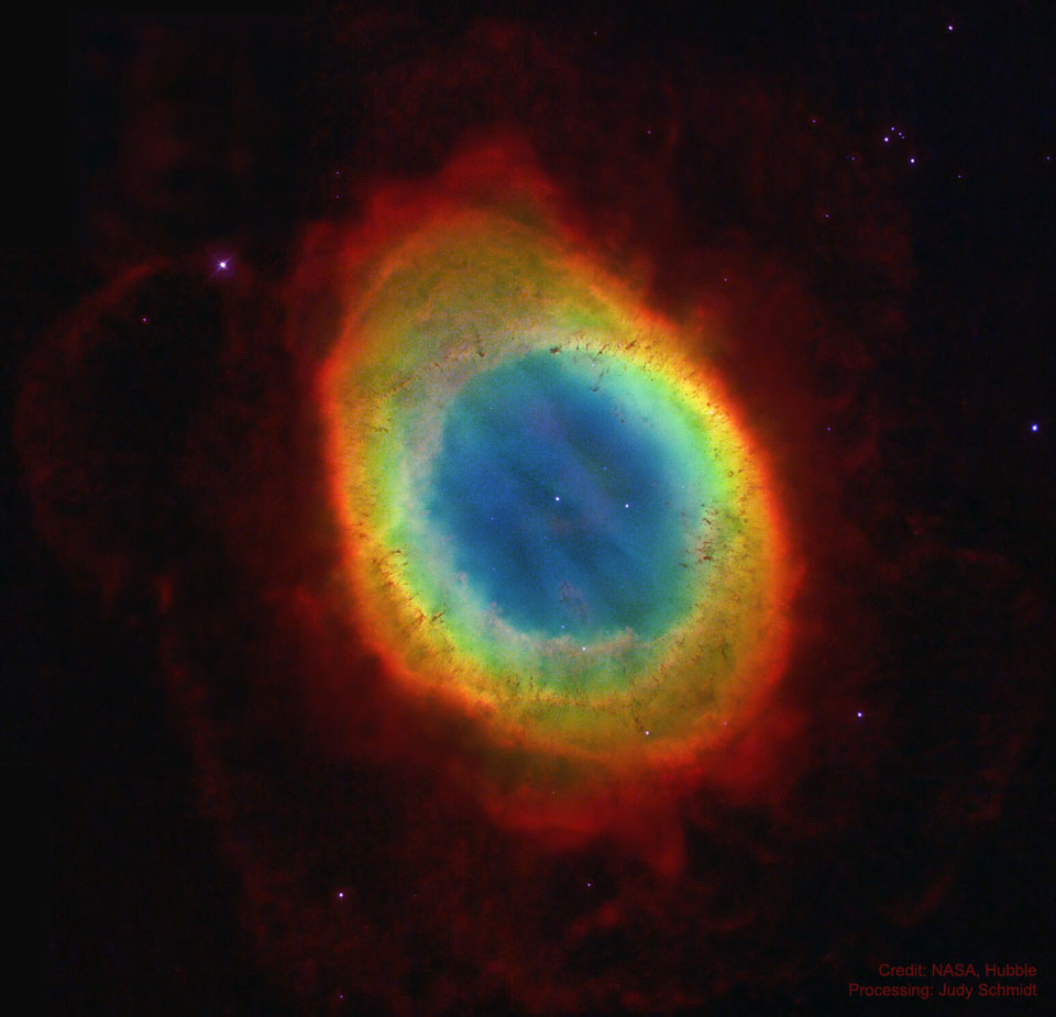 Vor einem dunklen Hintergrund leuchtet ein Ring in Regenbogenfarben, der innen ein zart blau leuchtendes Zentrum hat.