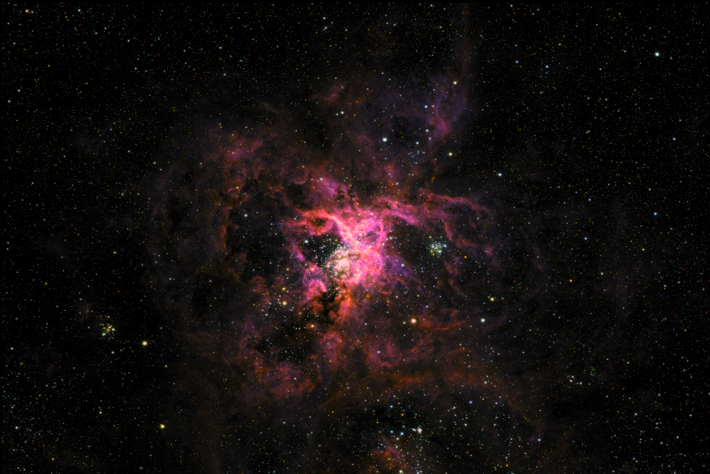 Die gefaserte, rötlich-magenta leuchtende Wolke in der Mitte erinnert an ein Spinnentier.