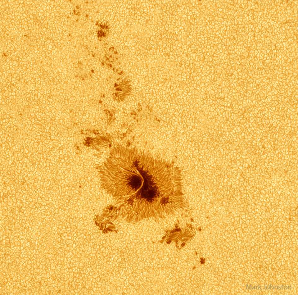 Auf der von Granulation überzogenen Sonnenoberfläche liegt ein dunkler Sonnenfleck mit Umbra und Penumbra.