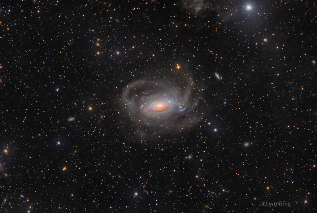 Inmitten eines Sternenfeldes leuchtet eine gelockte Spiralgalaxie mit ausladenden, verzerrten Spiralarmen.