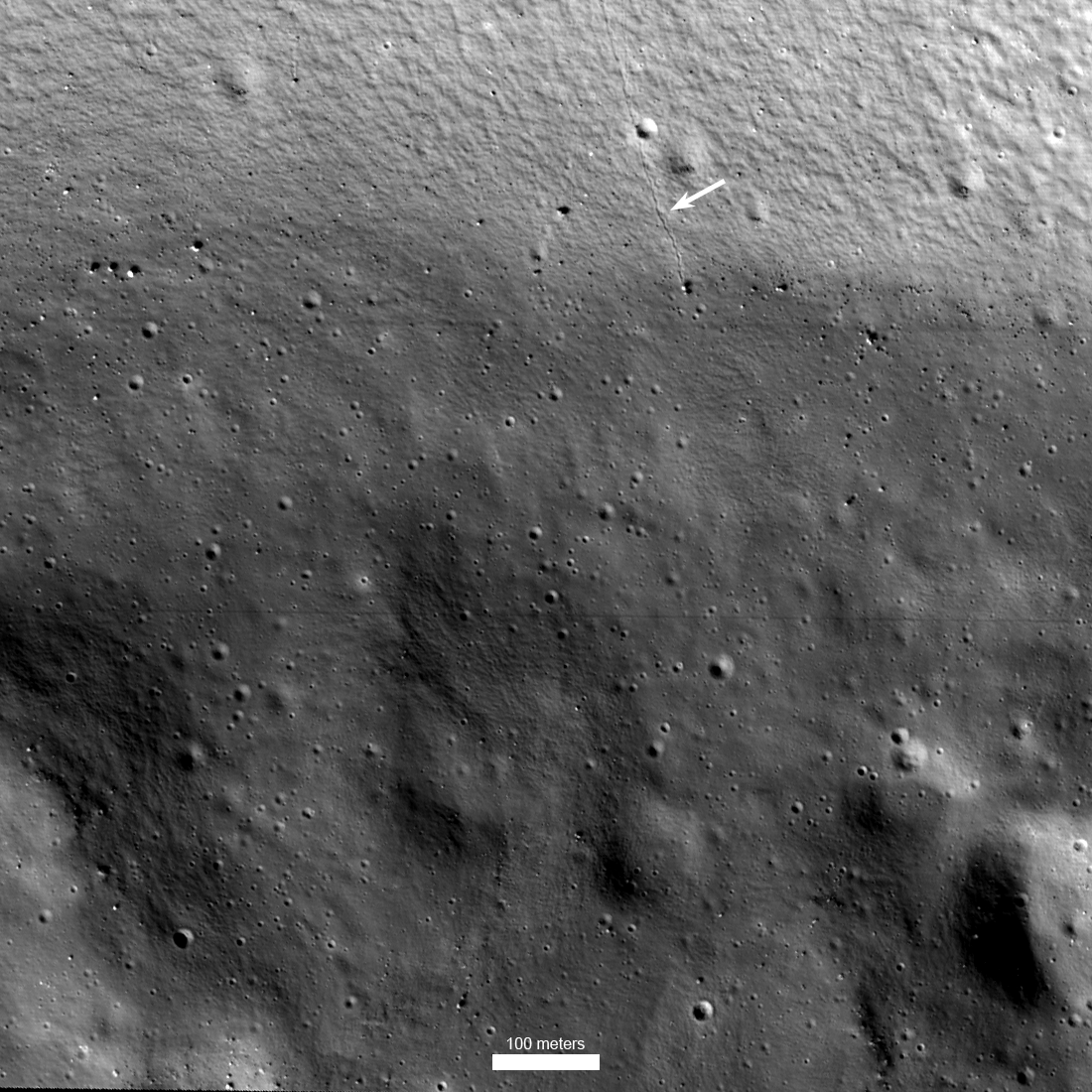 Auf dem schwarzweißen Bild des Kraters Shackleton auf dem Mond ist am oberen Bildrand eine Rille erkennbar, sie ist mit einem weißen Pfeil markiert.