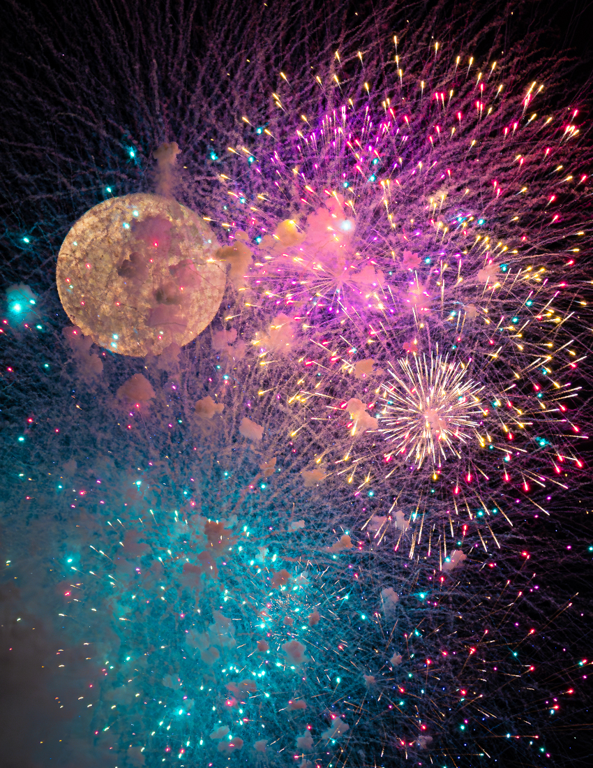 Hinter einem farbenprächtigen Feuerwerk ist nur mit Mühe der Vollmond erkennbar.