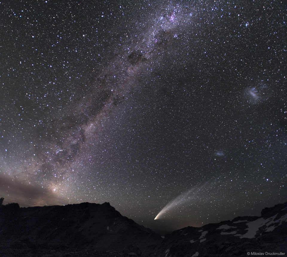 Am dunklen Himmel sind unter der diagonalen Milchstraße die beiden Magellanschen Wolken und ein heller Komet zu sehen.