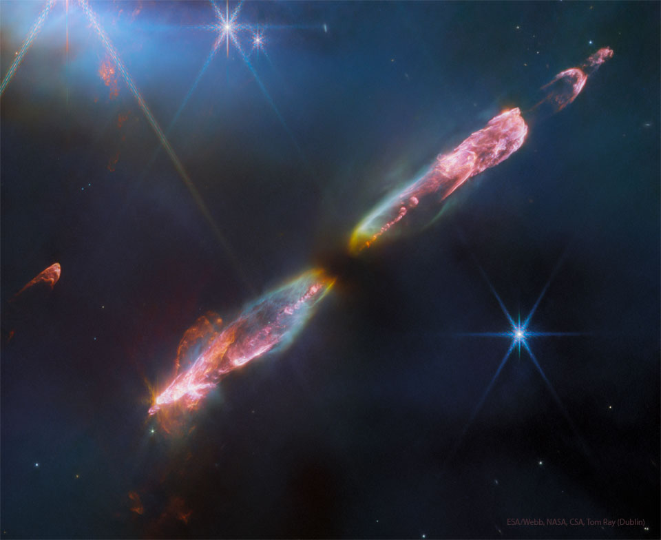 Ein Strom aus heißem, rötlich leuchtendem Gas verläuft diagonal durchs Bild. Einige Sterne mit den charakteristischen Strahlen des JWST sind im Bild verteilt.