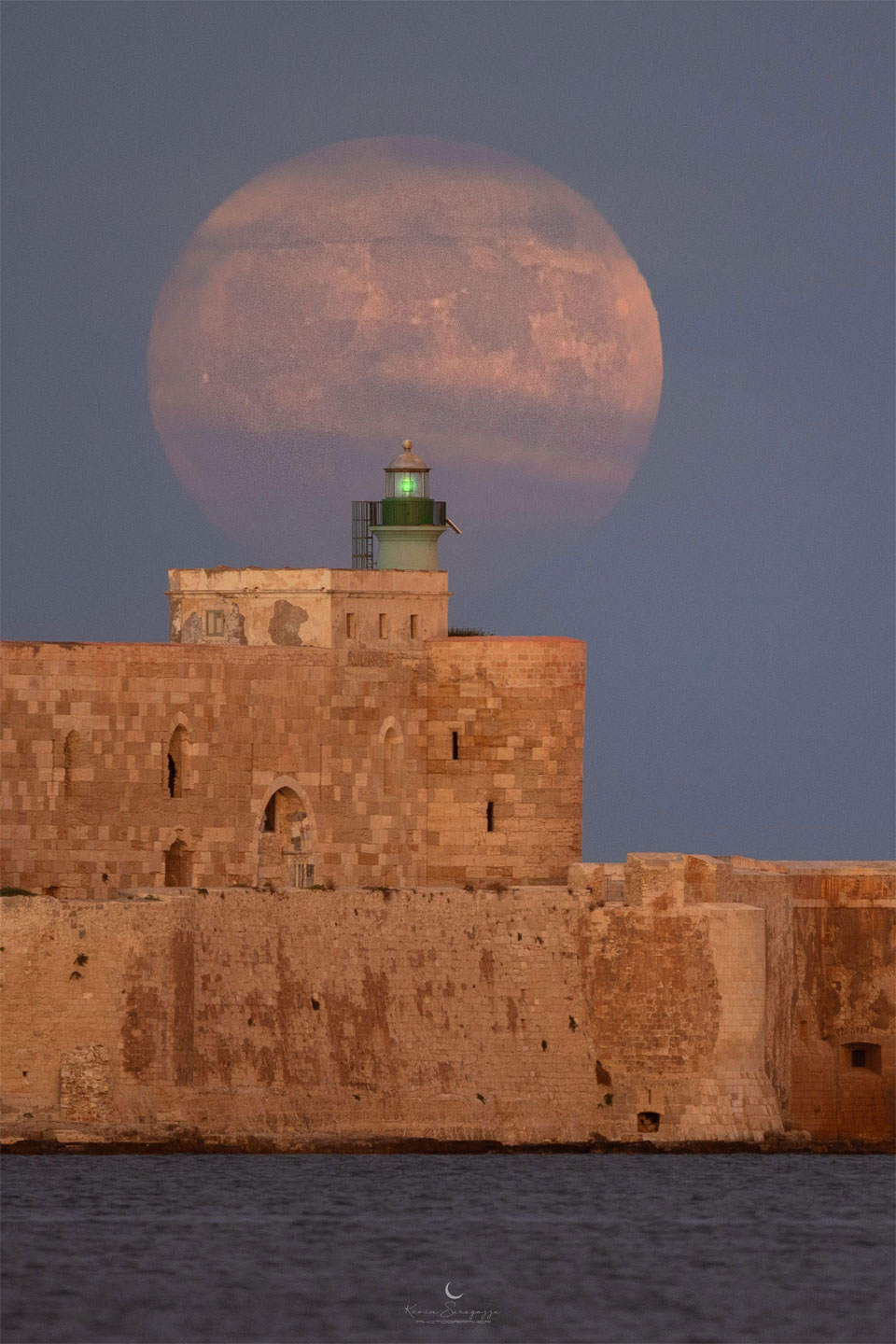 Über einem historischen Leuchtturm von Syrakus auf Sizilien schwebt der als "blauer Supermond" bezeichnete Vollmond im August.