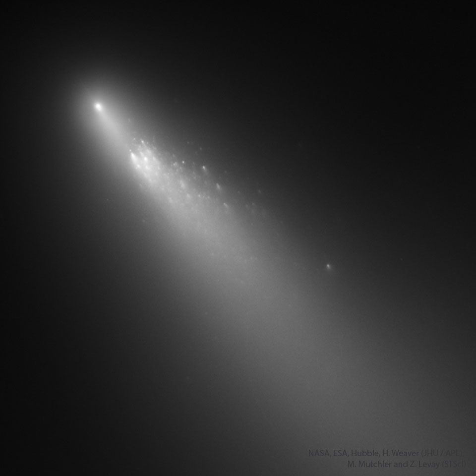 Diagonal im Bild sind leuchtende Trümmer des Kometen Schwassmann-Wachmann 3, umgeben von einem Schweif der von links oben nach links unten verläuft.
