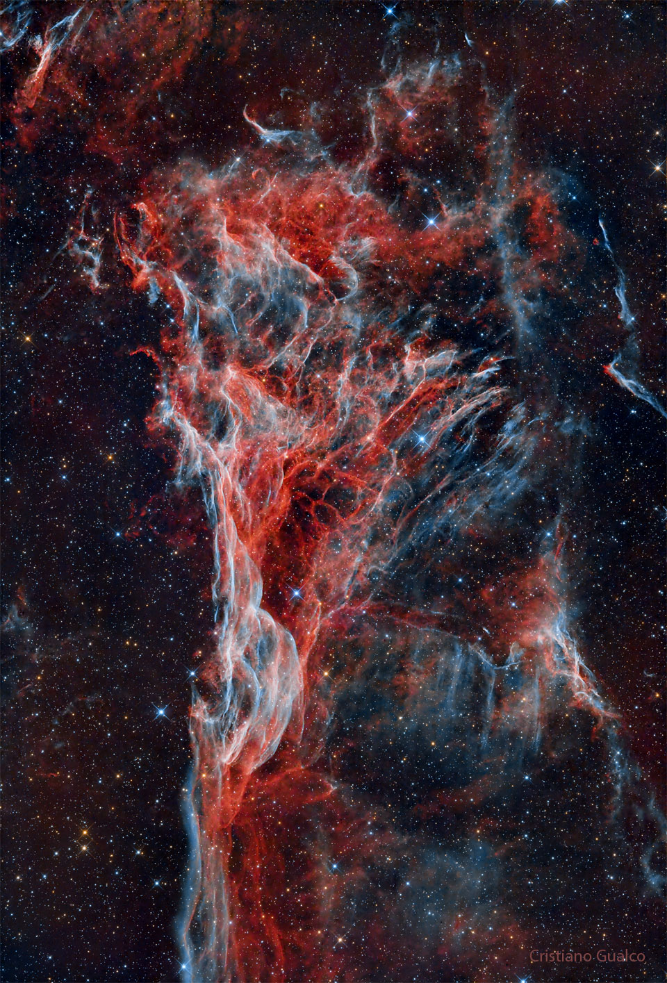 Vor dem Hintergrund, der mit Sternen gesprenkelt ist, breiten sich rot-blau-weiße Fasern aus, die eine entfernt dreieckige Form haben.