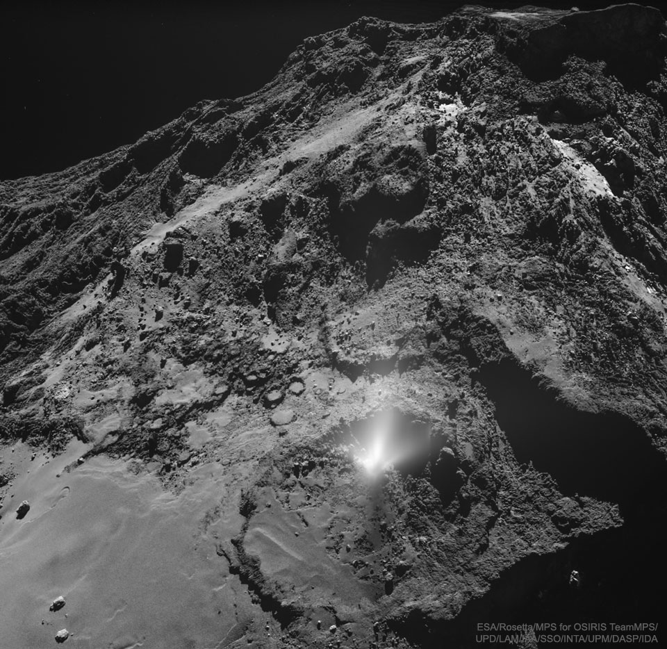 Auf der rauen Oberfläche des Kometen 67P ist im Vordergrund ein heller Ausbruch zu sehen.