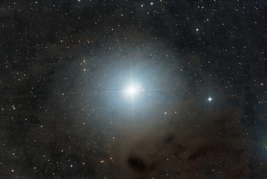 Epsilon Tauri: Stern mit Planet, umgeben von einem blau leuchtenden Nebel. Ein Klick auf das Bild zeigt es in Originalgröße an.