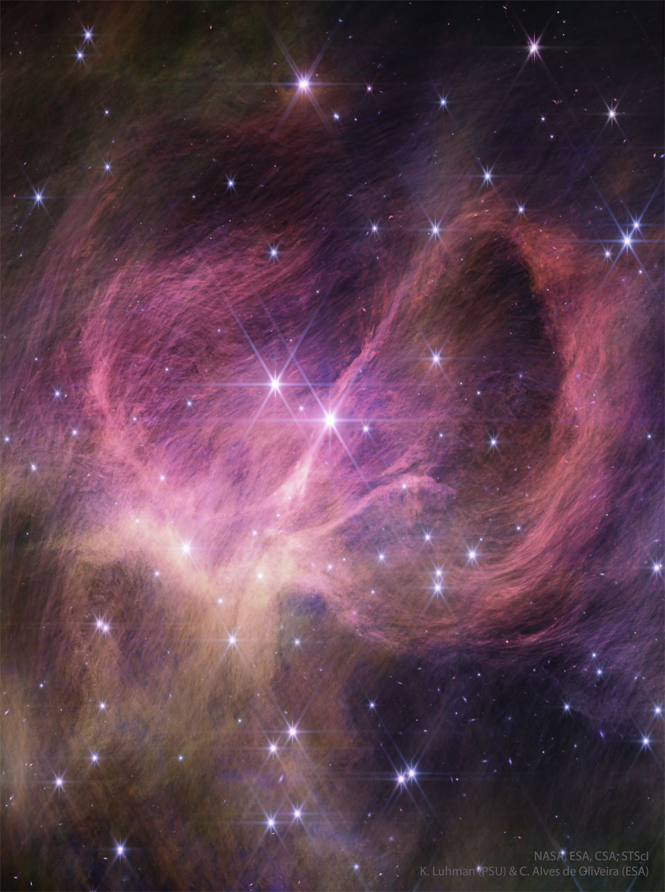 Im Bild ist ein stark gefaserter, lila leuchtender Nebel sowie zahlreiche helle Sterne mit Zacken abgebildet.