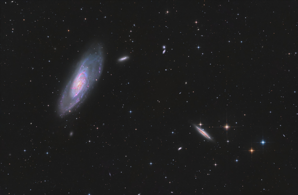Im Bild sind mehrere Galaxien verteilt, links oben ist die größte, sie ist schräg von der Seite zu sehen und wirkt etwas unregelmäßig.