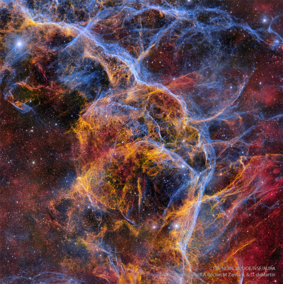 Das Bild zeigt ein Gemisch aus orangefarbenen und zartblauen Stoßwellen in einem Supernovaüberrest.