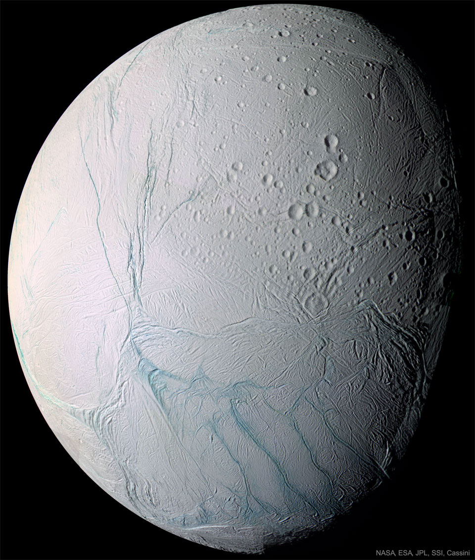 Bildfüllend ist der eisige Saturnmond Enceladus dargestellt. Rechts oben an der Schattenlinie sind Krater, die restliche Oberfläche ist von Rillen überzogen. Die Rillen haben einen blauen Farbton, der Rest des Mondes wirkt grau.