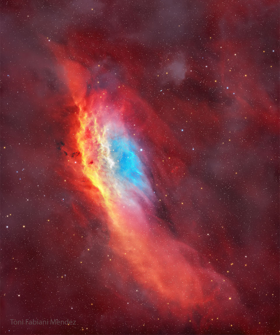 Der leuchtend rote Nebel im Bild erinnert wegen seiner Form an den US-Bundesstaat Kalifornien. In der Mitte liegt ein blauer Nebel mit einem orangegelben Streifen links daneben.