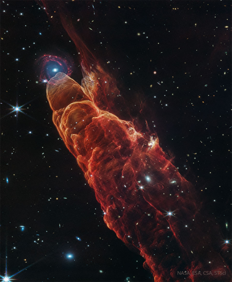 Eine Gaswolke türmt sich diagonal im Bild auf. Ihre äußere Hülle ist rot leuchtend dargestellt.An ihrer Spitze befindet sich eine Spiralgalaxie, die jedoch weit hinter der Wolke liegt. 