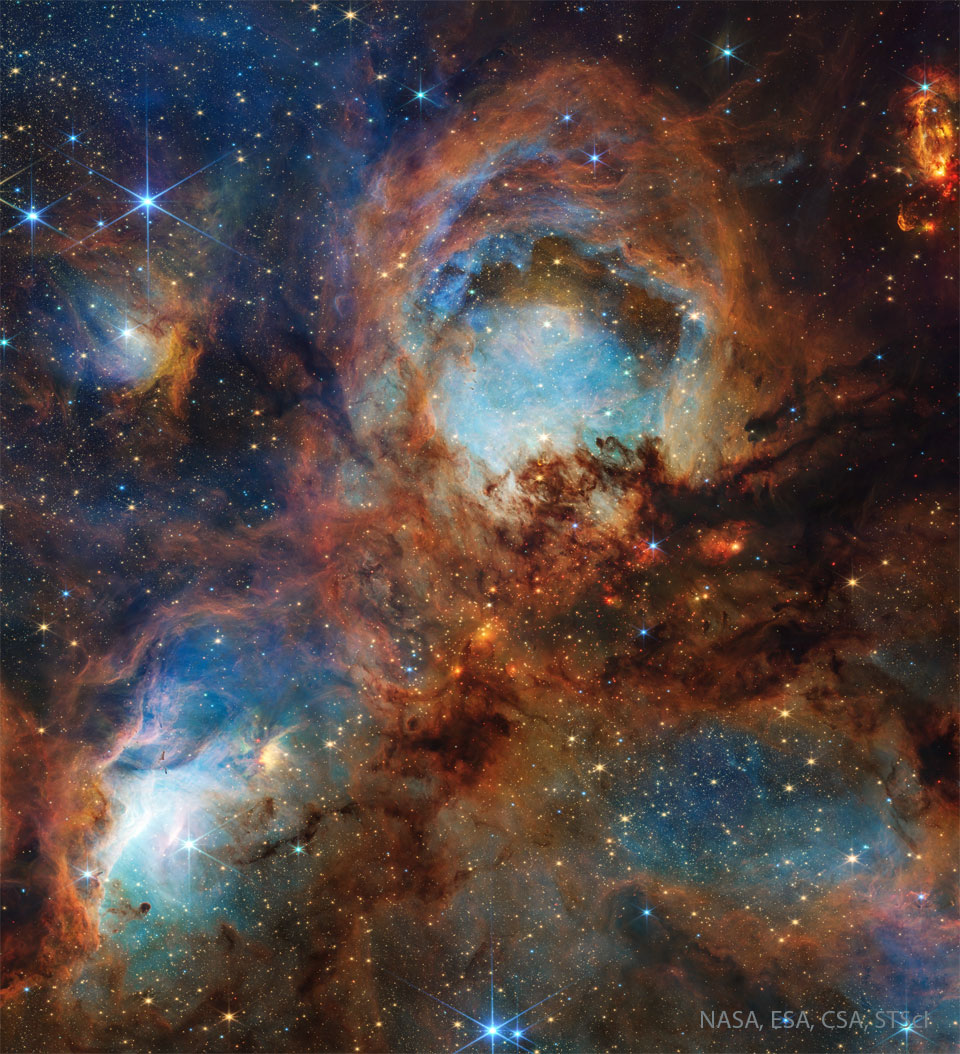 Drei rundliche bläuliche Nebelwolken mit einem bräunlichen Nebelrand eingehüllt in weitere bräunliche Nebelschwaden vor einem Sternenhintergrund. Ein Klick auf das Bild lädt die höchstaufgelöste verfügbare Version.