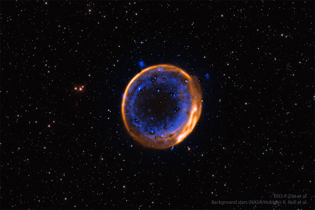 Zwischen lose verteilten Sternen leuchtet ein Ring. Er ist außen orange-braun und glatt, innen blau und wolkig.