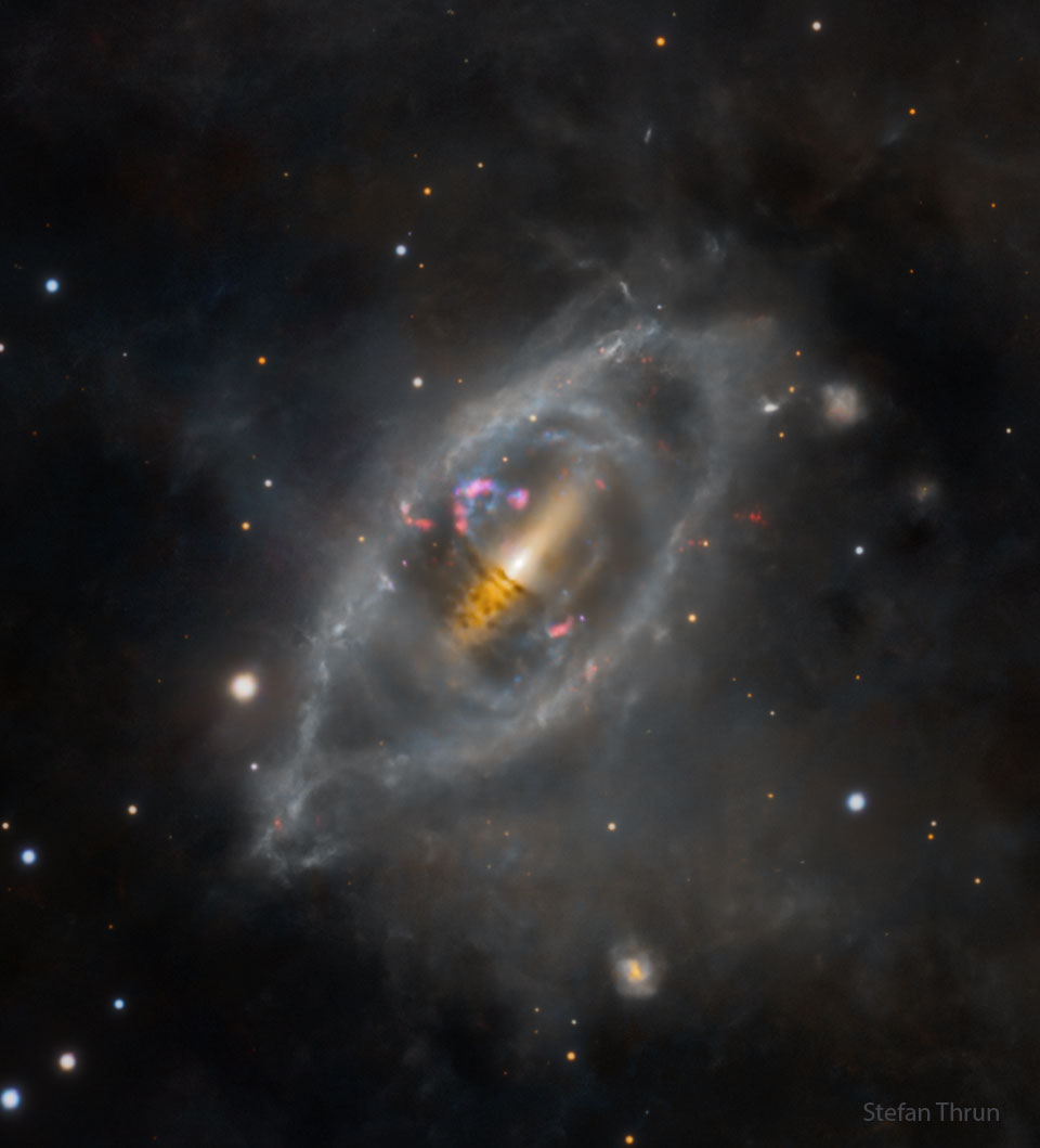 Die Polarring-Galaxie NGC 2685 ist länglich, in der Mitte ist sie von einem Geflecht aus dunklem Staub umgeben, das wie ein Band oder ein Ring aussieht.
