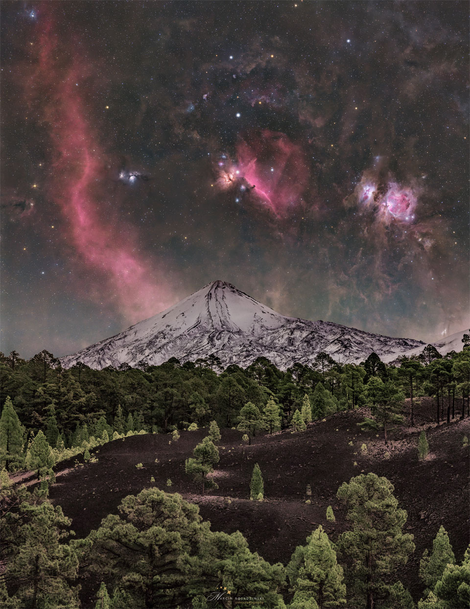 Über dem Teide, einem Vulkan auf der Kanarischen Insel Teneriffa, schimmern die rötlichen Emissionsnebel im Sternbild Orion: der Orionnebel, der Flammennebel, die Barnardschleife und der Nebel, in den der dunkle Pferdekopf gekerbt ist.
