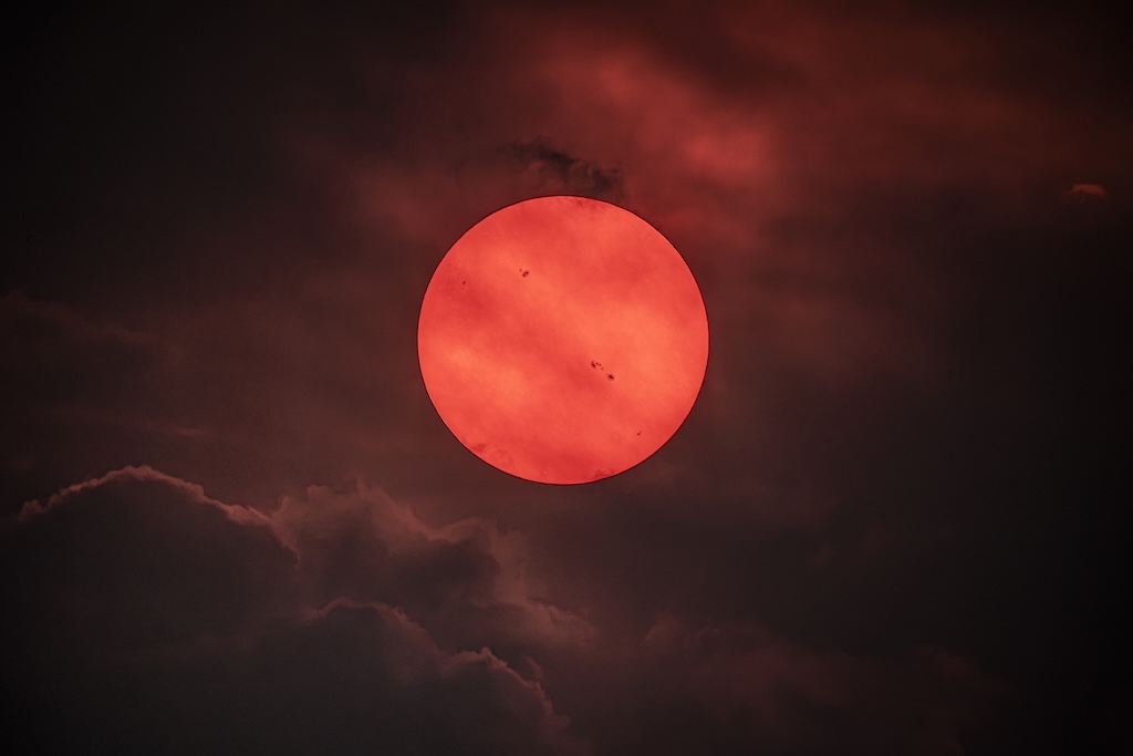 Die Szene wirkt wie die Animation eines roten Zwergsterns, den man auf einem fiktiven Exoplaneten sieht. Doch der Stern ist unsere Sonne. Sie leuchtet rot, weil die Rauchwolken eines Waldbrandes sie verdunkeln.