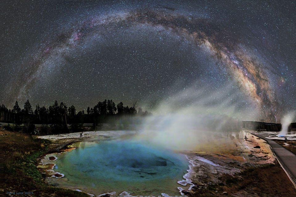 Über dem künstlich beleuchteten Silex Spring, dessen türkise Farbe von Bakterien stammt, wölbt sich die Milchstraße. Aus dem Tümpel steigt Dampf aus, weil das Wasser vom Yellowstone-Hotspot erhitzt wird.